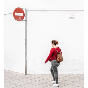 fotografo-señal-vertical-prohibido-chica-sueter-rojo-mochila-pared-blanca.jpg