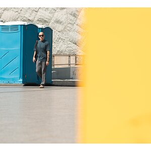 fotografo-callejear-persona-gafas-sol-calvo-cabina-baños-azul-amarillo.jpg